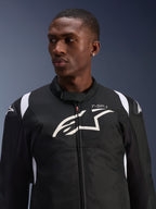 Alpinestars T-SP 1 V2 Waterproof Jacket gedragen door een model, zwart-witte textiele motorjas, groot wit Alpinestars-logo en T-SP-1-branding op de borst, sportief ontwerp met beschermende schoudersliders