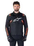 Alpinestars T-SPS V2 Waterproof jas, Black White en Red Fluo, gedragen door een mannelijk model met zwarte motorhandschoenen, voorzien van een groot wit Alpinestars-logo op de borst en levendige oranje accenten op de schouders en mouwen.