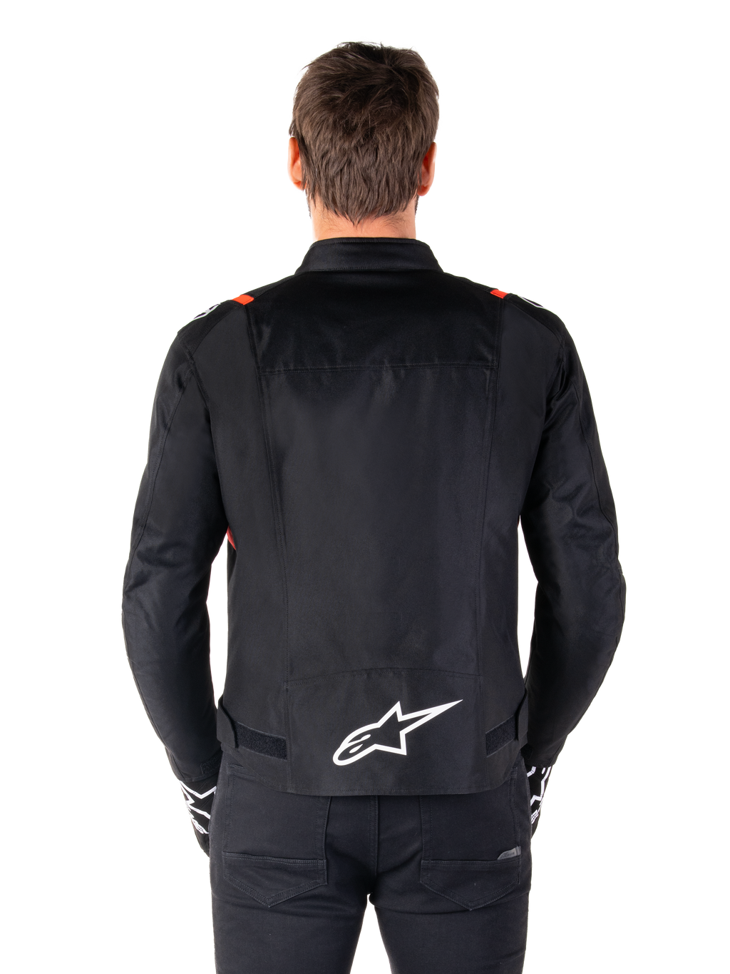 Alpinestars T-SPS V2 Waterproof Jacket, zwart met witte en rood fluo accenten, achteraanzicht met een groot wit Alpinestars-logo op de onderrug, sportieve textiel motorjas, gedragen met zwarte broek en handschoenen