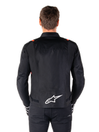 Alpinestars T-SPS V2 Waterproof Jacket, zwart met witte en rood fluo accenten, achteraanzicht met een groot wit Alpinestars-logo op de onderrug, sportieve textiel motorjas, gedragen met zwarte broek en handschoenen