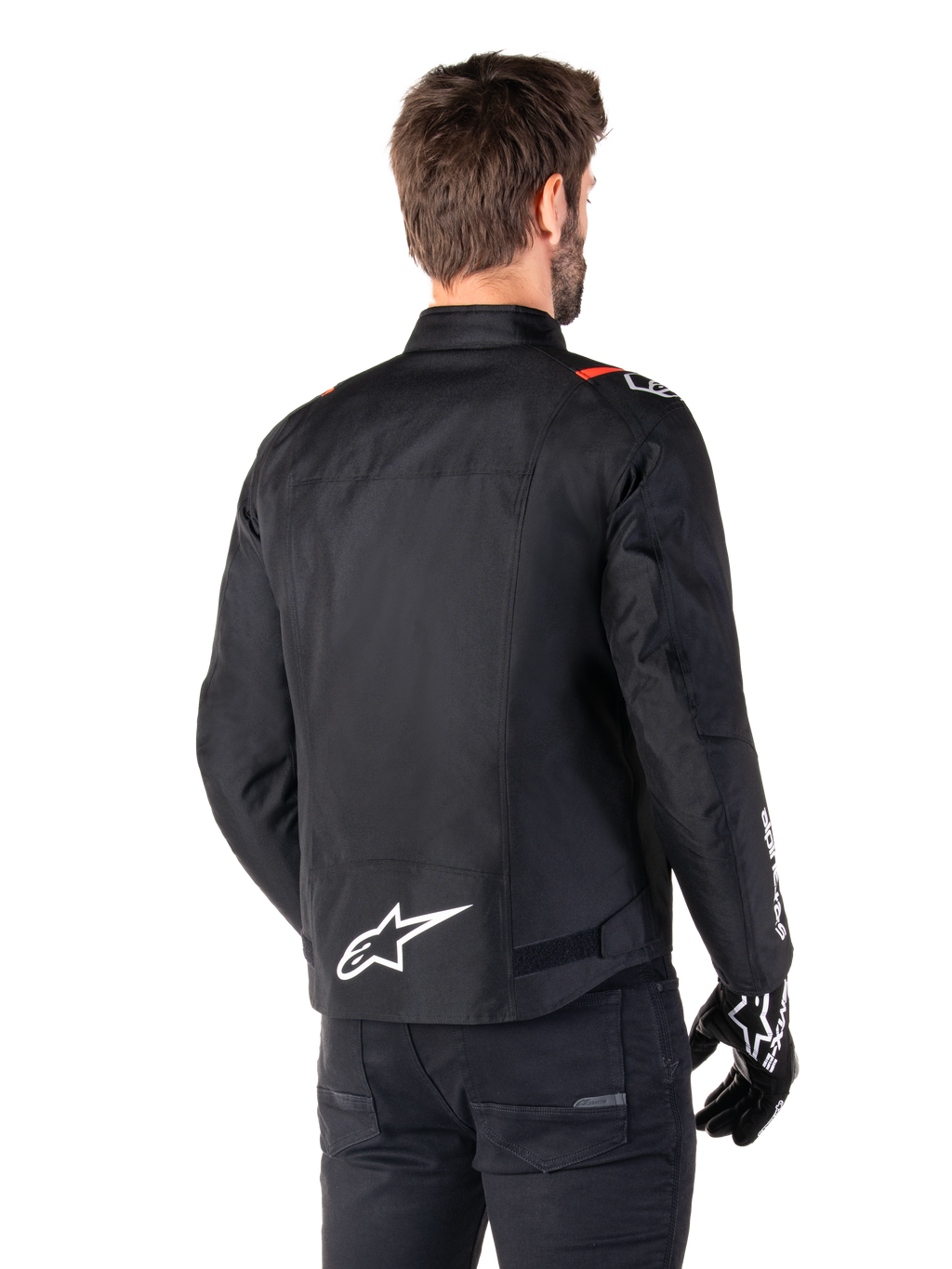 Alpinestars T-SPS V2 Waterproof Jas, Zwart Wit Rood Fluo, achteraanzicht, met wit Alpinestars-logo op de onderrug en rode accenten op de schouders, gedragen met zwarte motorhandschoenen en broek, sportieve textiele motorjas