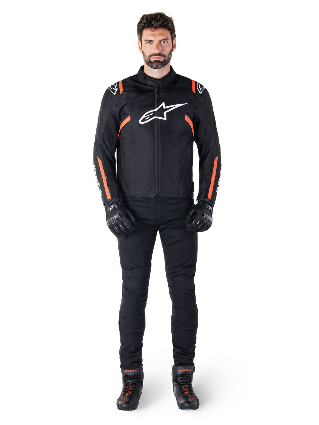 Mannelijk model draagt de Alpinestars T-SPS V2 Waterproof Jacket in Black White Red Fluo, gecombineerd met een zwarte motorbroek en handschoenen, voorzien van een wit Alpinestars-logo op de borst en rode accenten op de mouwen.