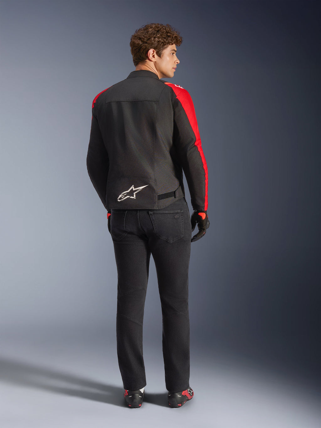 Alpinestars T-SPS V2 Waterproof Jacket, Black Red Red Fluo, back view on male model, white Alpinestars logo on the lower back, worn with black motorcycle pants and gloves, sporty textile waterproof riding jacket