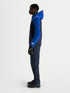 Alpinestars Aeroshell WP jas, waterdichte herenmotorjas in nachtblauw en felblauw met capuchon en softshell-constructie, gedragen door een model in profielweergave.