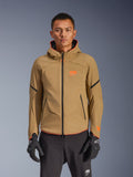 Alpinestars Aeroshell Waterproof Jacket, donker kaki motorjas met capuchon, oranje logo's en zwarte ritsen, zwarte accentlijnen op de mouwen, getoond met zwarte handschoenen en broek