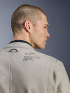 Alpinestars Borrego Drystar® Jas in Warm Gray, close-up van de achterschouder, getextureerd gewaxt canvas materiaal, met zwart Alpinestars-logo en heritage-tekst, gedragen door model, adventure motorjas