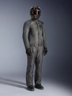 Motorrijder in de Alpinestars Borrego Drystar® Jas in Warm Gray, volledige adventure-uitrusting met bijpassende grijze broek, zwarte integraalhelm met motorbril en zwarte handschoenen, voorzien van een strak waterdicht textielontwerp.