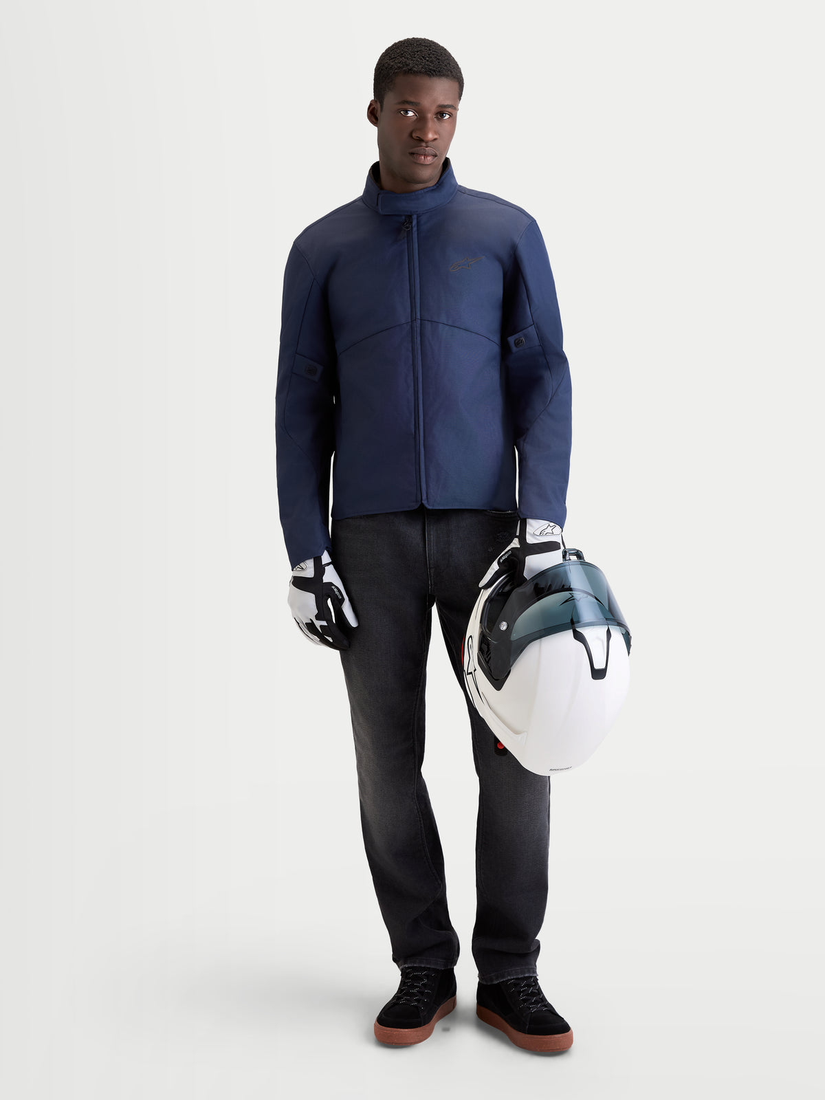 Alpinestars C-1 Waterproof Jas, heren urban contemporary motorjas in donkerblauw, vooraanzicht op model met bijpassende handschoenen en een witte helm, waterdichte motorkleding voor koude en natte omstandigheden