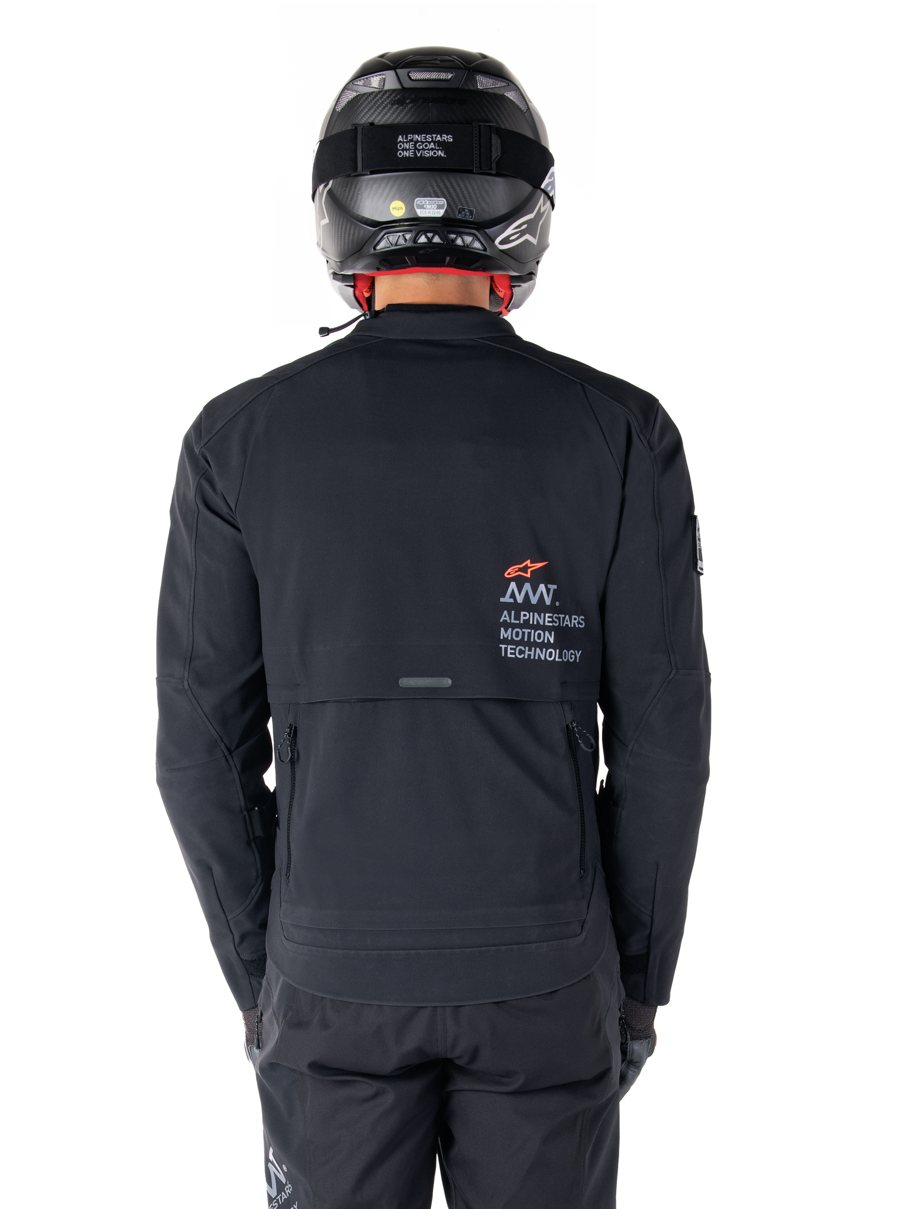 Alpinestars AMT-8 Stretch Drystar® XF Jas, achteraanzicht, zwart, gedragen met een zwarte helm en broek, met Alpinestars Motion Technology-branding op de rug, adventure touring-ontwerp met ergonomisch stretchmateriaal.