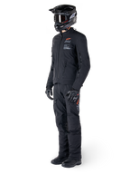 Alpinestars AMT-8 Stretch Drystar® XF jas, adventure motorjas, zwart, gedragen met bijpassende broek, helm en handschoenen, voorzien van Alpinestars Motion Technology branding met oranje accenten, duurzame stretchconstructie voor adventure rijden