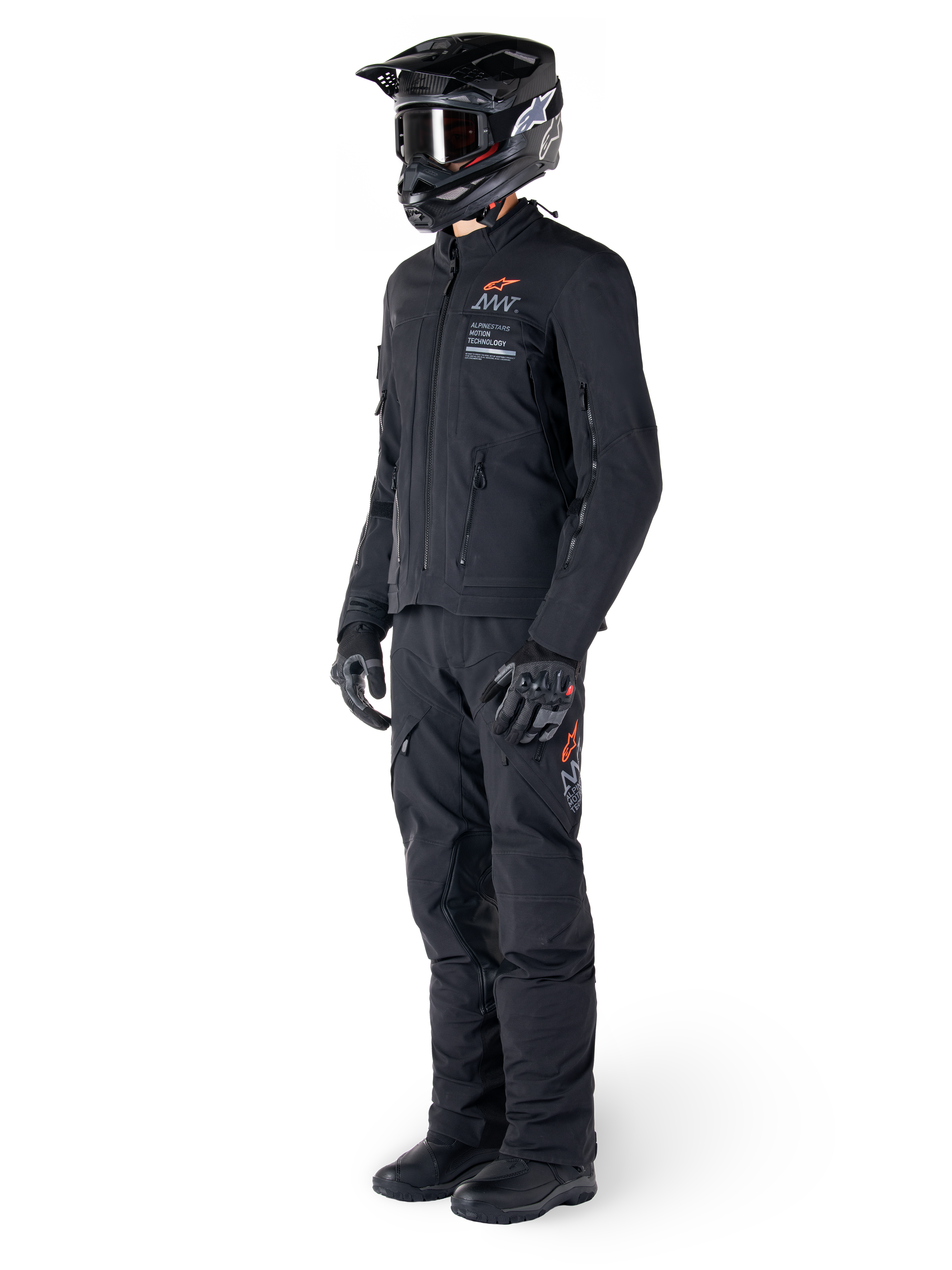 Alpinestars AMT-8 Stretch Drystar® XF jas, adventure motorjas, zwart, gedragen met bijpassende broek, helm en handschoenen, voorzien van Alpinestars Motion Technology branding met oranje accenten, duurzame stretchconstructie voor adventure rijden