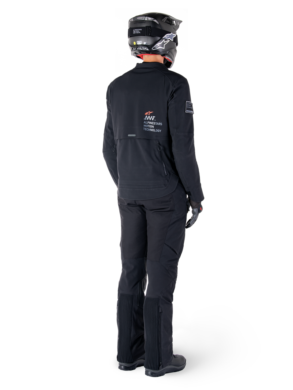 Alpinestars AMT-8 Stretch Drystar® XF Jas, zwart, achteraanzicht van een motorrijder die de jas draagt met bijpassende zwarte broek en een zwarte helm, voorzien van 'Alpinestars Motion Technology' branding op de rug, technisch stretchmateriaal voor adventure motorrijden