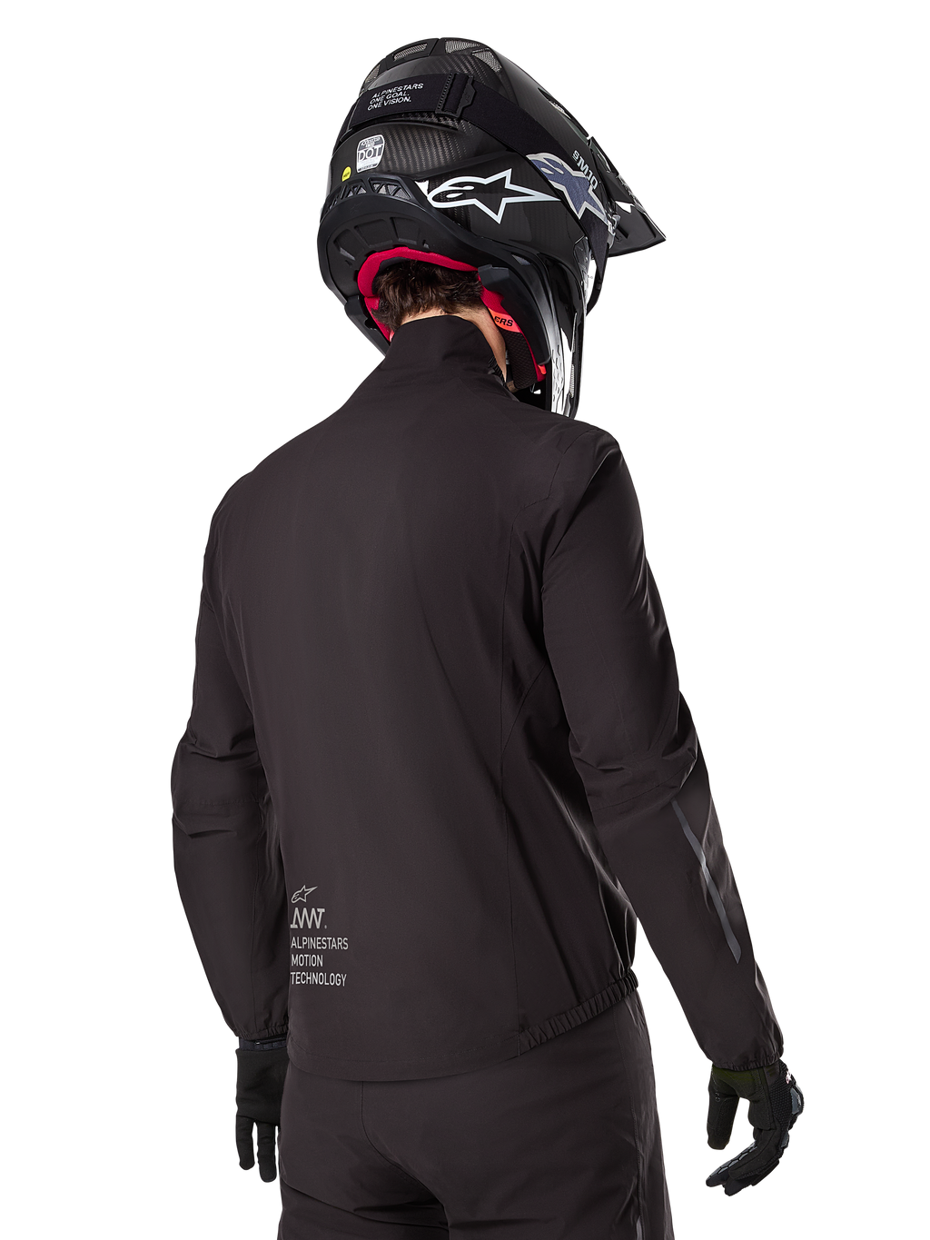 Alpinestars AMT-8 Stretch Drystar® XF voering, zwarte waterdichte voering voor motorjas, achteraanzicht van een rijder met zwarte helm en handschoenen, voorzien van Alpinestars Motion Technology-branding op de onderrug, minimalistisch en functioneel ontwerp voor adventure ritten.