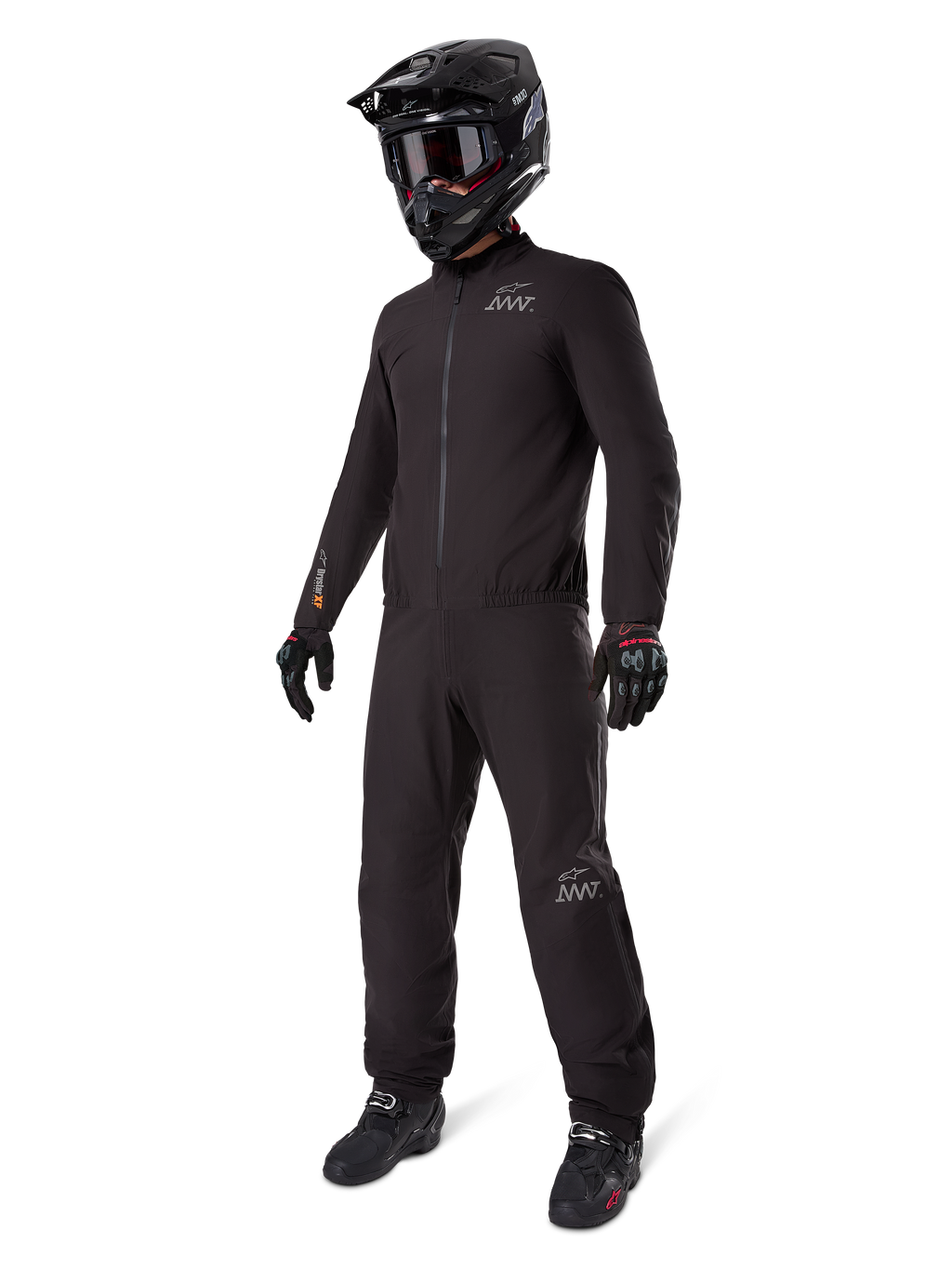 Alpinestars AMT-8 Stretch Drystar® XF Liner, zwart waterdicht motorpak, gedragen met zwarte helm, motorbril en handschoenen, voorzien van AMT- en Drystar XF-branding, functionele adventure-uitrusting voor bescherming in alle weersomstandigheden.