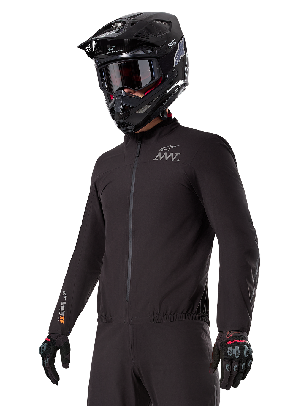 Rijder draagt de Alpinestars AMT-8 Stretch Drystar® XF Liner, zwarte wind- en waterdichte stretchjas, met AMT-logo op de borst en Drystar XF-branding op de mouw, gecombineerd met een zwarte adventure-helm en beschermende handschoenen.