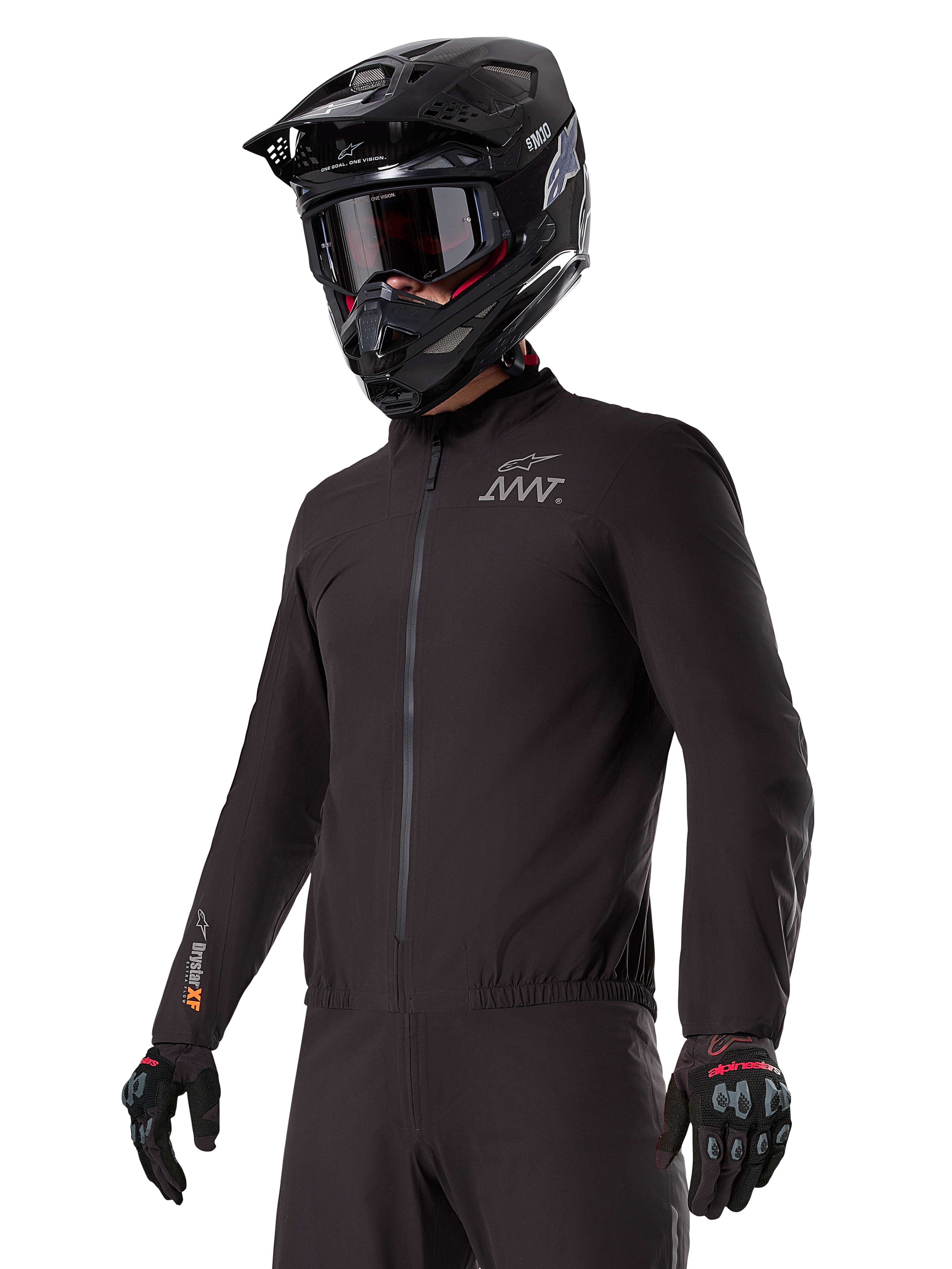 Rijder draagt de Alpinestars AMT-8 Stretch Drystar® XF Liner, zwarte wind- en waterdichte stretchjas, met AMT-logo op de borst en Drystar XF-branding op de mouw, gecombineerd met een zwarte adventure-helm en beschermende handschoenen.