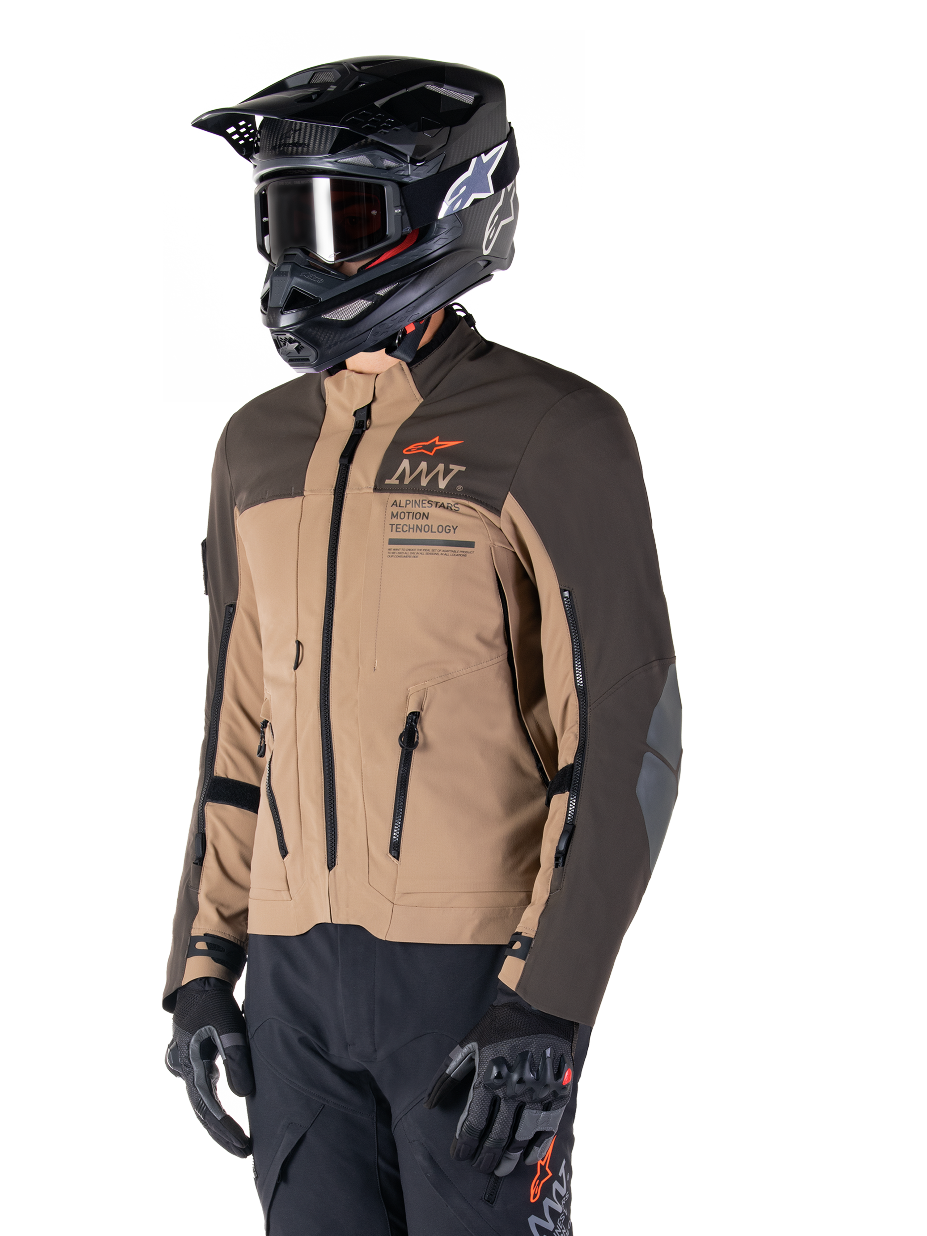 Alpinestars AMT-8 Stretch Drystar® XF Jas, adventure motorjas, donkerbruin en donker khaki, gedragen met een zwarte off-road helm en crossbril, voorzien van Alpinestars Motion Technology-branding en ventilatieopeningen met ritssluiting.