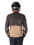 Alpinestars AMT-8 Stretch Drystar® XF Jas, achteraanzicht, donkerbruin en donkerkhaki tweekleurig ontwerp, voorzien van Alpinestars Motion Technology-branding, cargozak met rits aan de achterkant en beschermende elleboogpanelen, adventure touring motorkleding