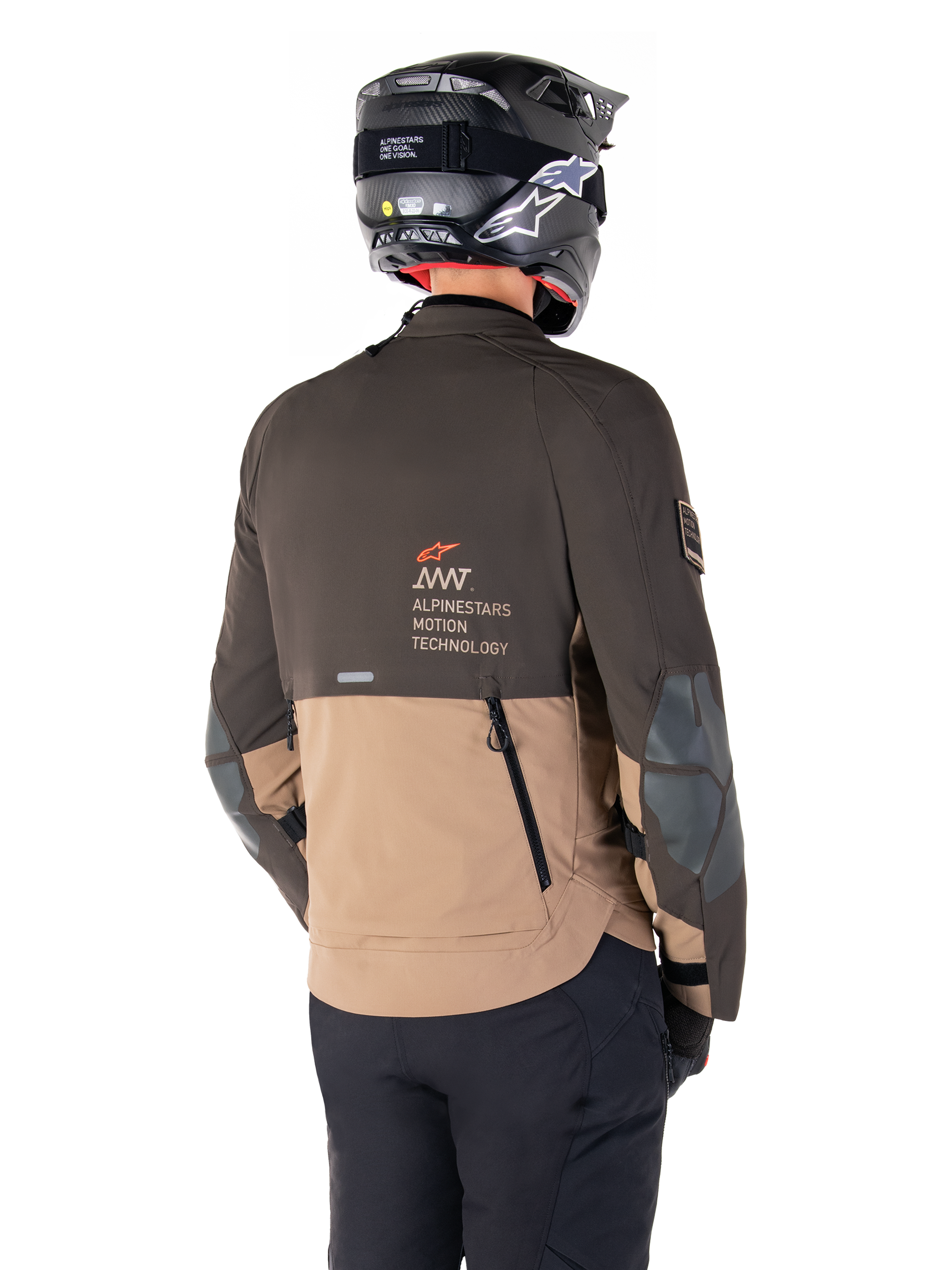 Alpinestars AMT-8 Stretch Drystar® XF Jas, adventure motorjas, donkerbruin en donkerkhaki, achteraanzicht met AMT Alpinestars Motion Technology branding, tweekleurig textielontwerp met ventilatieritsen op de rug en dakpanontwerp, gedragen met zwarte helm en motorbroek