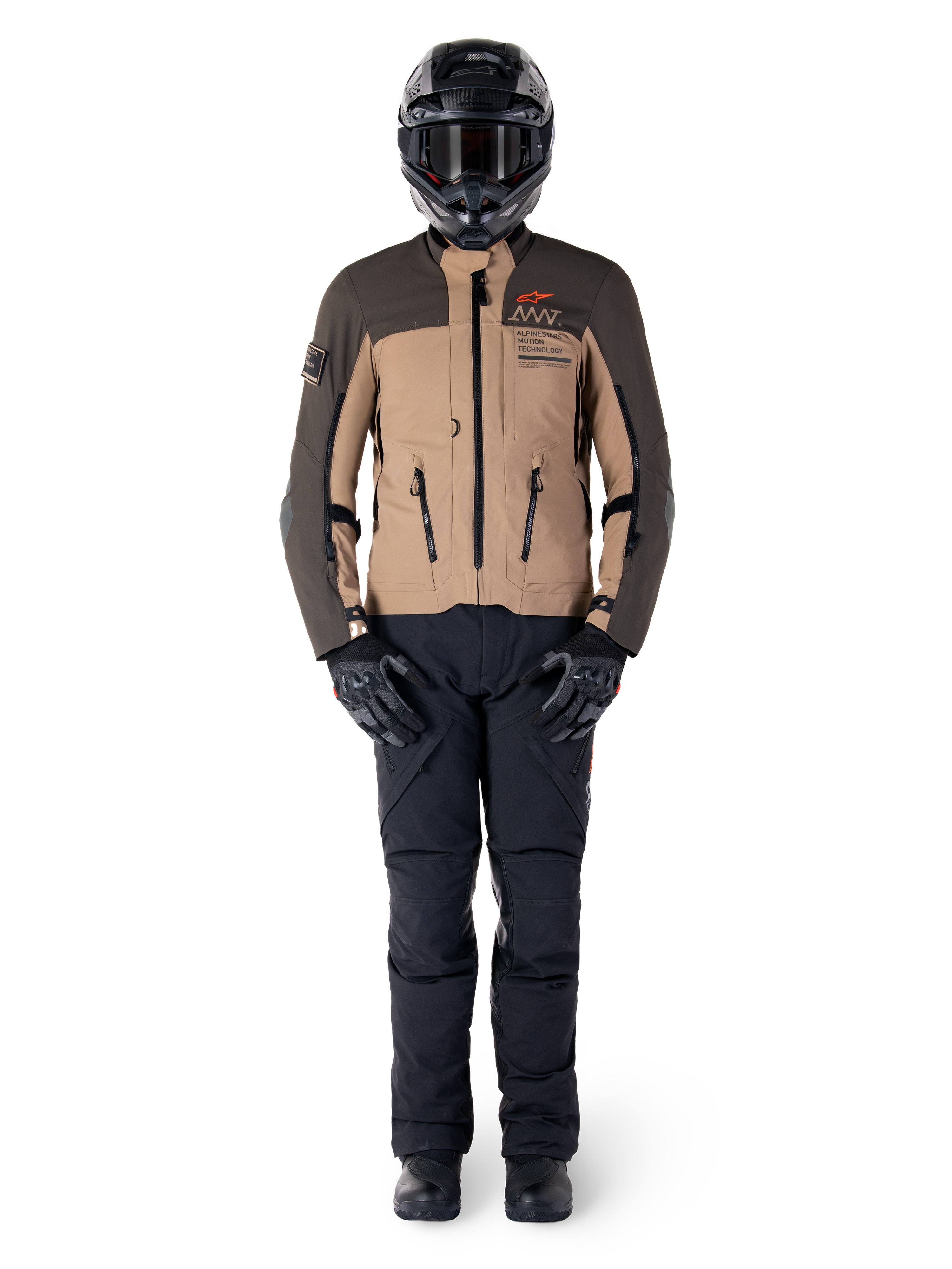 Alpinestars AMT-8 Stretch Drystar® XF Jas, adventure motorjas, donkerbruin en donkerkhaki, gedragen met een zwarte helm, motorbril, zwarte handschoenen, zwarte broek en zwarte laarzen, voorzien van ventilatieopeningen op de borst en AMT-branding, gecoördineerde uitrusting voor adventure touring