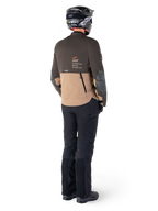 Alpinestars AMT-8 Stretch Drystar® XF Jas, adventure touring motorjas, donkerbruin en donkerkhaki, achteraanzicht met 'AMT Alpinestars Motion Technology' branding, gedragen met zwarte broek en helm, ergonomisch stretchontwerp voor adventure-rijden