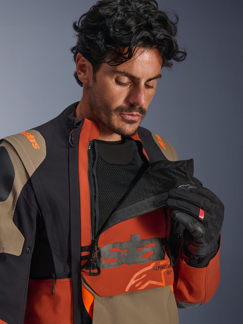 Alpinestars Halo Pro Drystar® XF gelamineerd jack, Walnut Rust Black kleurstelling, mannelijk model demonstreert modulair ventilatiesysteem door het borstpaneel open te ritsen om zwart mesh te onthullen, technisch adventure motorjack met roestbruine en beige accenten.
