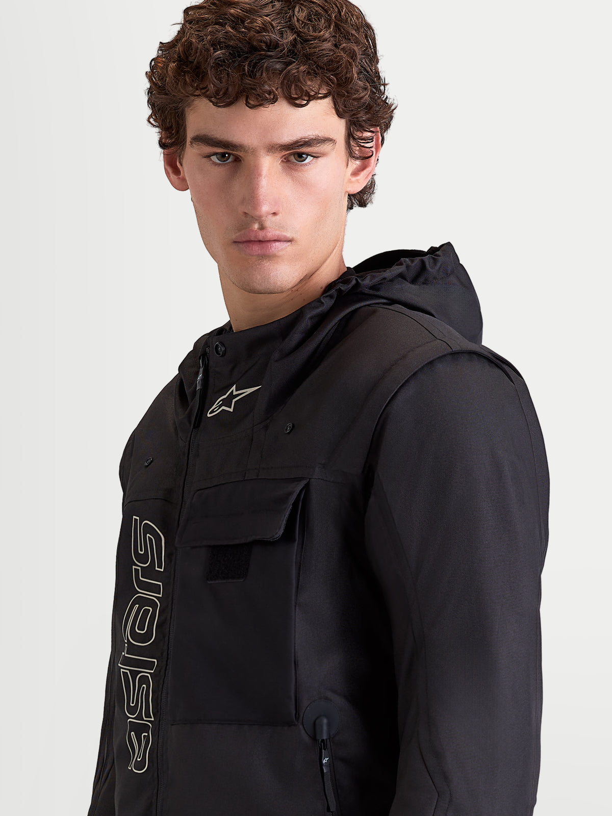 Alpinestars Morfex Parka Waterproof Jacket, heren motorjas in het zwart, portret van een model met de jas en een geïntegreerde capuchon en borstzakdetails