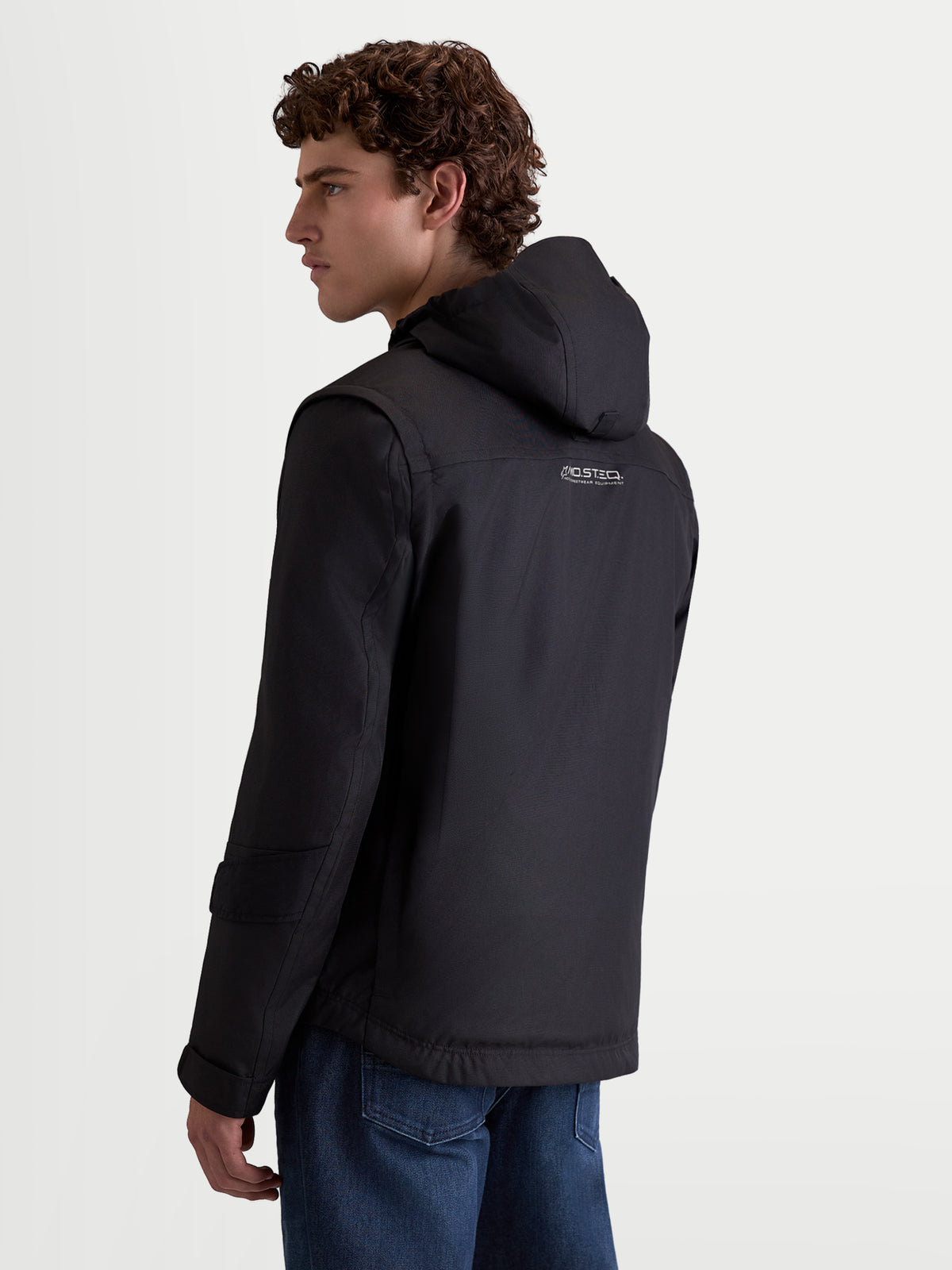 Alpinestars Morfex Parka motorjas, heren urban contemporary motorjas in zwart, achteraanzicht op model die de textiel motorjas draagt met geïntegreerde capuchon