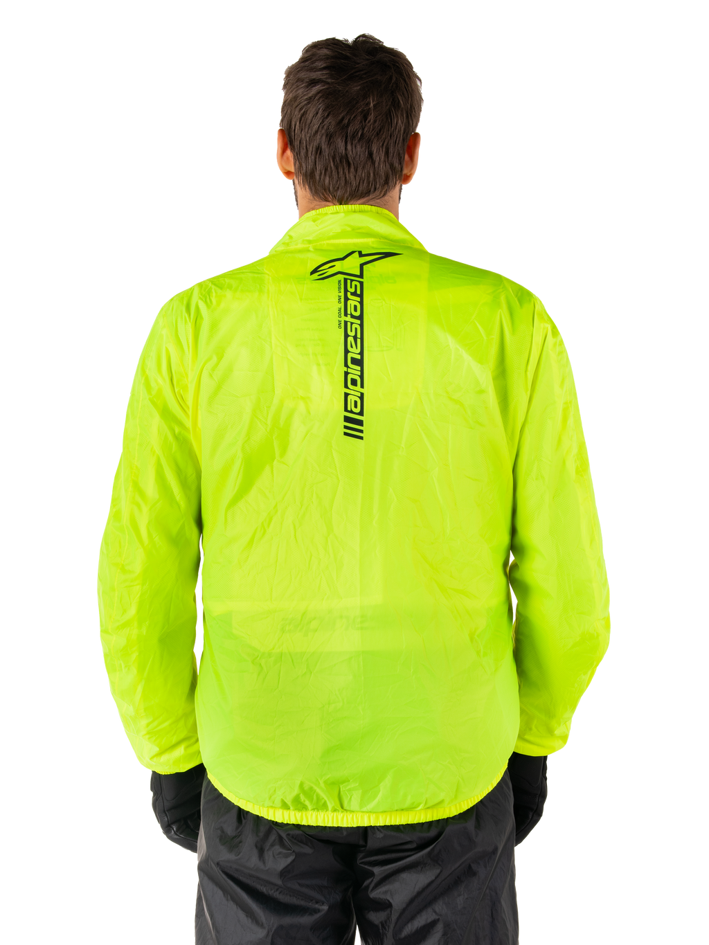 Alpinestars Hurricane Rain V2 Jacket, motorregenjas, Yellow Fluo, achteraanzicht met verticaal zwart Alpinestars-logo midden op de rug, lichtgewicht waterdichte stof, gedragen met zwarte motorbroek en handschoenen