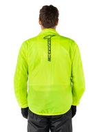 Alpinestars Hurricane Rain V2 Jacket, motorregenjas, Yellow Fluo, achteraanzicht met verticaal zwart Alpinestars-logo midden op de rug, lichtgewicht waterdichte stof, gedragen met zwarte motorbroek en handschoenen