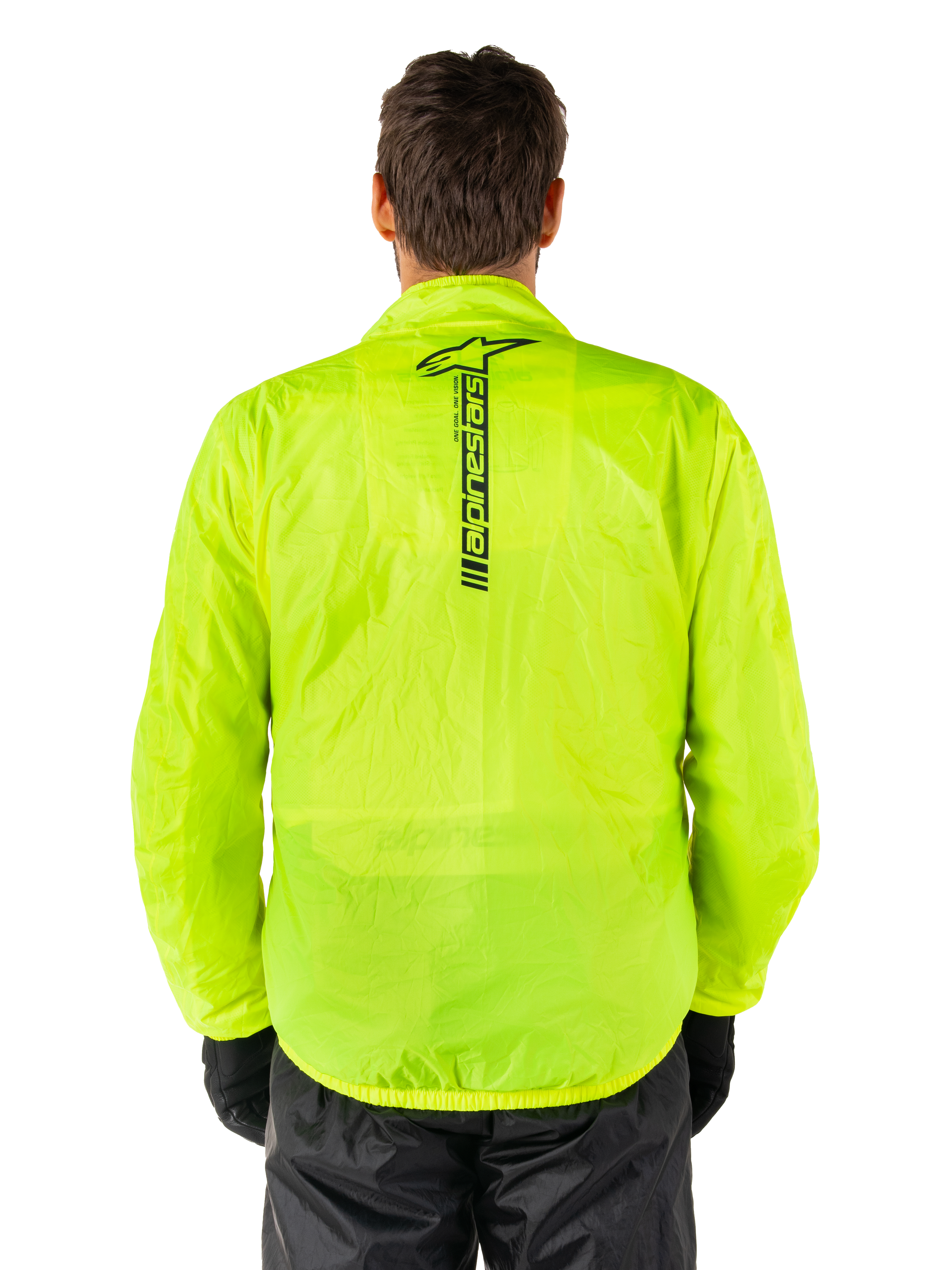 Alpinestars Hurricane Rain V2 Jacket, motorregenjas, Yellow Fluo, achteraanzicht met verticaal zwart Alpinestars-logo midden op de rug, lichtgewicht waterdichte stof, gedragen met zwarte motorbroek en handschoenen