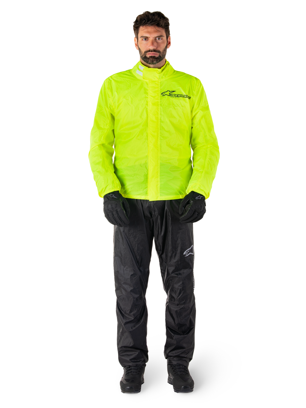 Alpinestars Hurricane Rain V2 jas en broek, neongeel en zwart, waterdicht motorregenpak gedragen met zwarte handschoenen en laarzen, voorzien van het Alpinestars-logo op de borst en het been