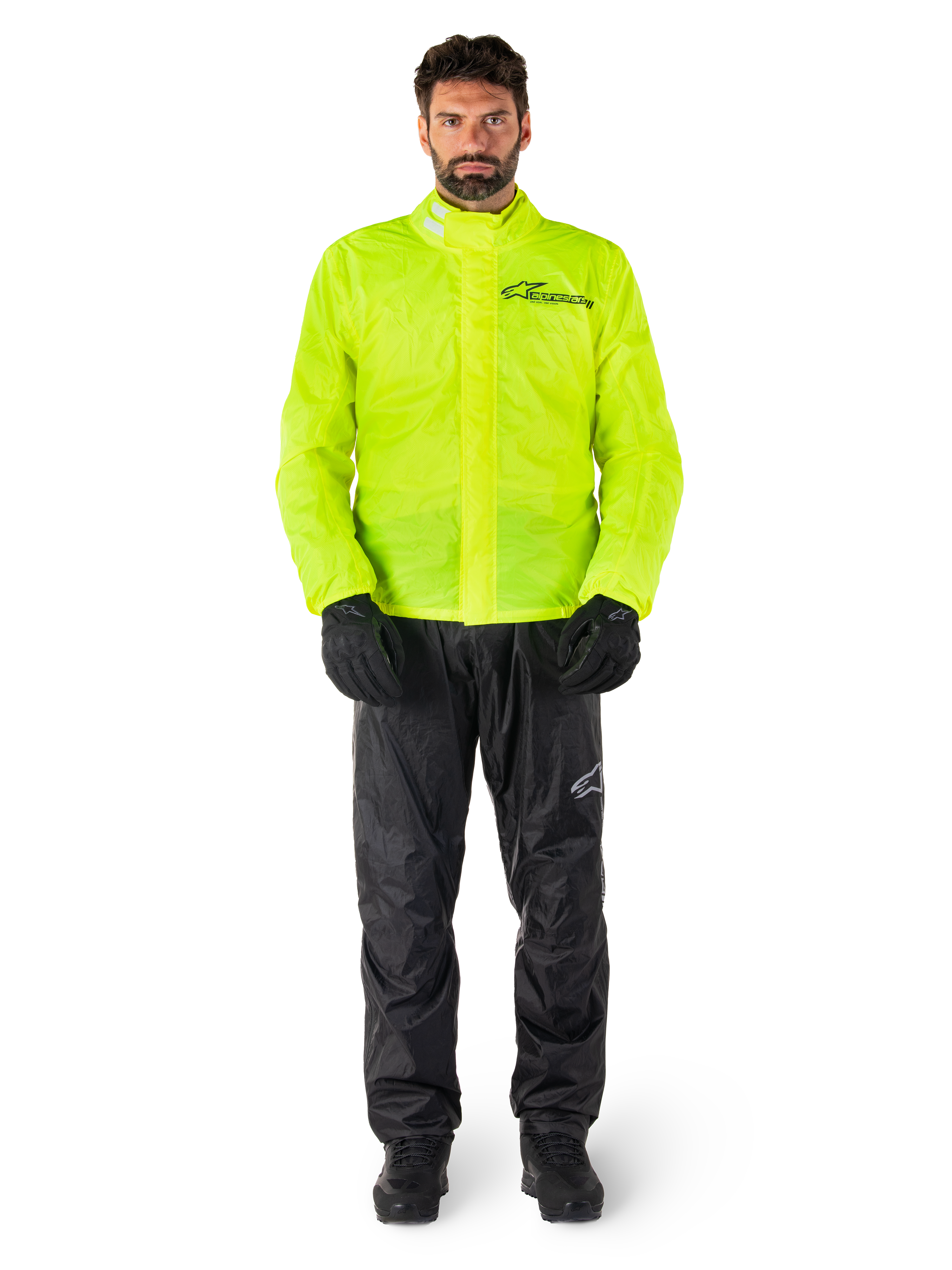 Alpinestars Hurricane Rain V2 jas en broek, neongeel en zwart, waterdicht motorregenpak gedragen met zwarte handschoenen en laarzen, voorzien van het Alpinestars-logo op de borst en het been