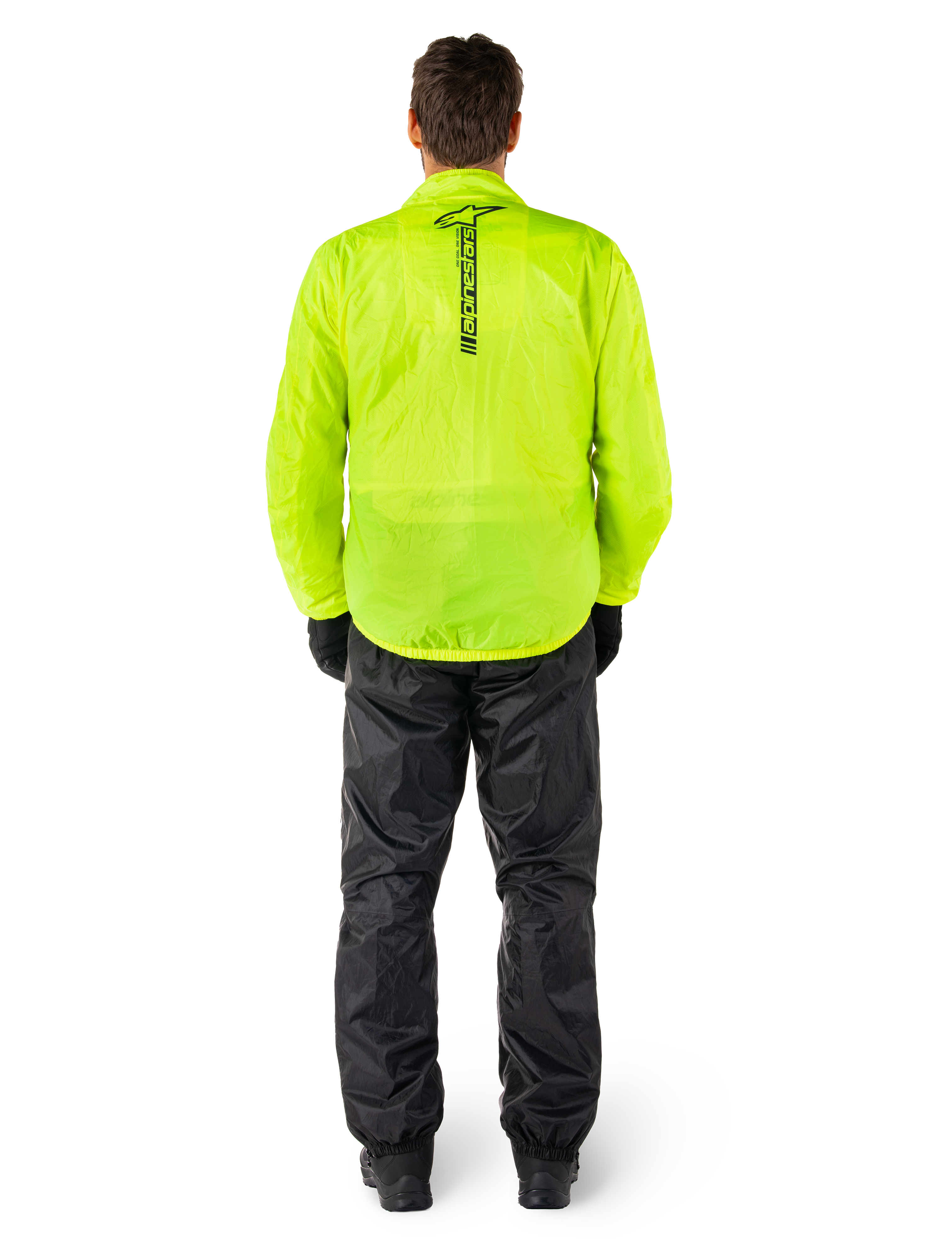 Alpinestars Hurricane Rain V2 jas en broek, waterdicht motorregenpak, fel fluorgele jas met verticaal zwart logo op de rug, zwarte broek, lichtgewicht textielmateriaal ontworpen voor bescherming in natte weersomstandigheden, persoon van achteren gezien