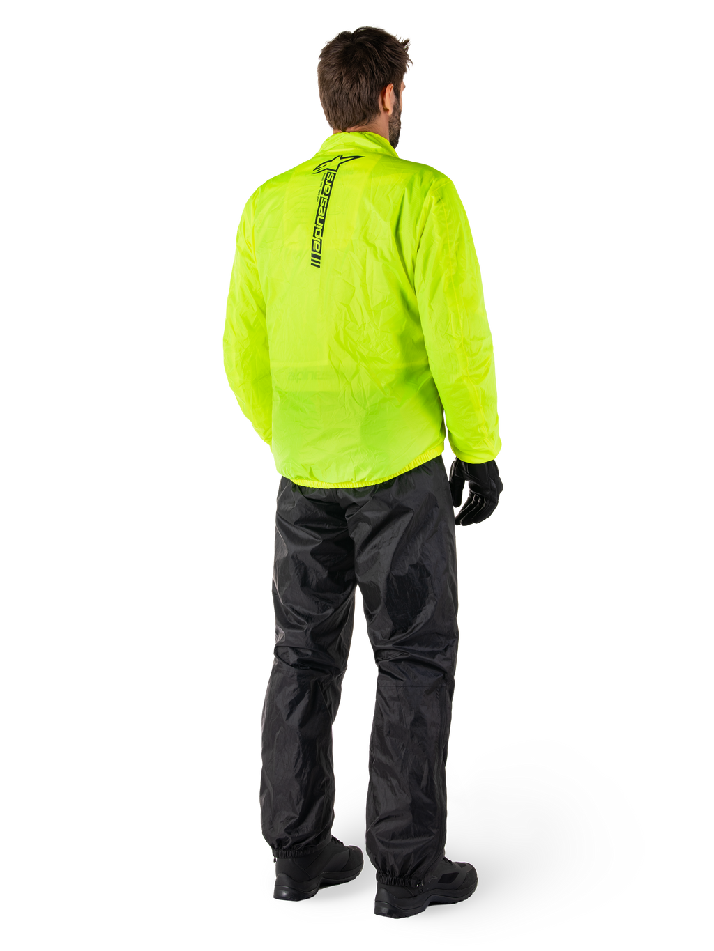Alpinestars Hurricane Rain V2 Jacket in Yellow Fluo en Hurricane Rain V2 Pant in Black, persoon van achteren gezien, verticaal logo op de rug van de jas, waterdichte motorregenkleding met zwarte handschoenen en laarzen