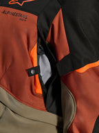 Alpinestars Andes V4 Drystar® Jas, Walnut Rust Black, close-up van directe ventilatieopening met mesh voering, duurzaam textielmateriaal met oranje accenten, drukknop en Alpinestars logo-detail