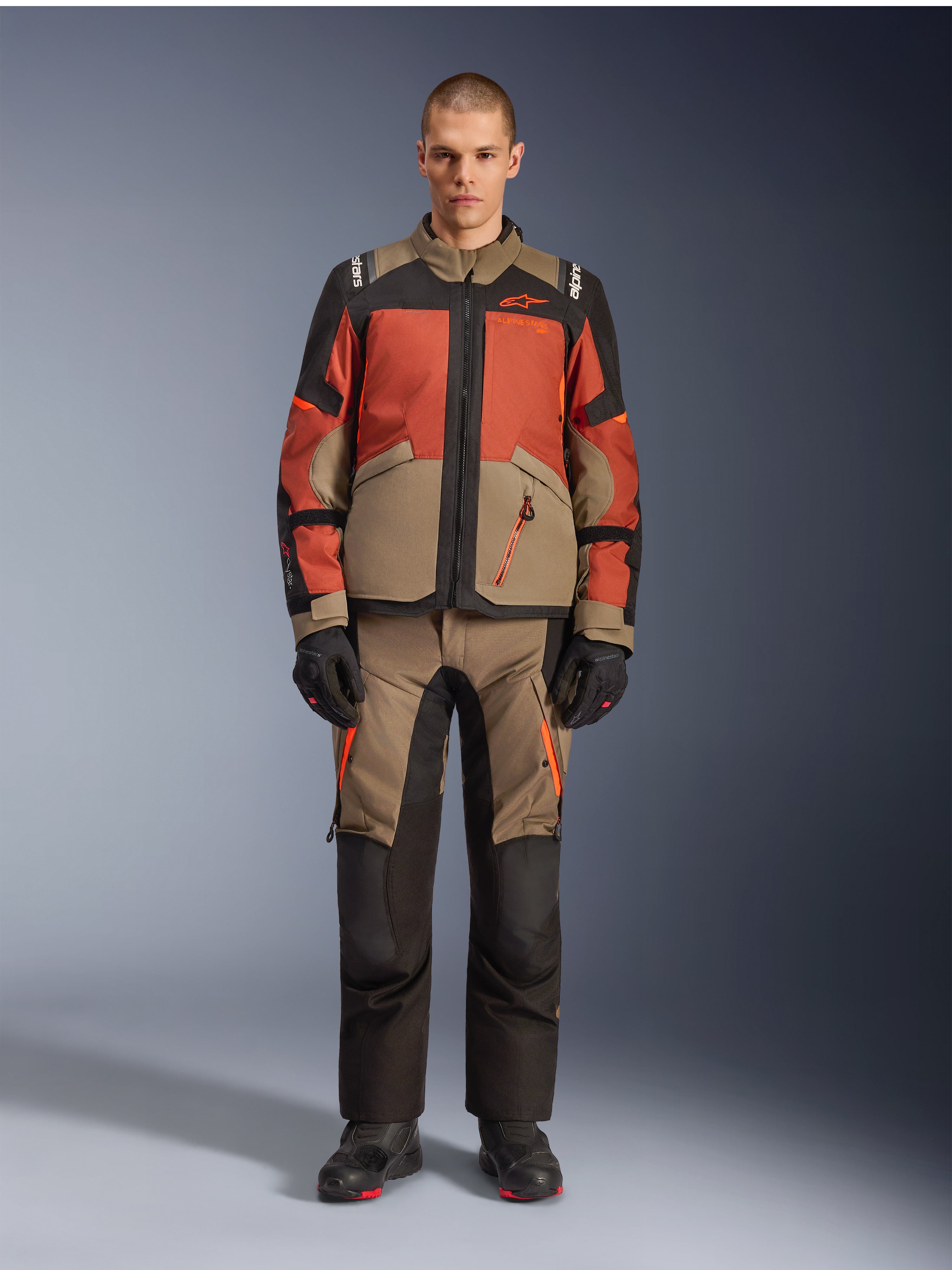 Alpinestars Andes V4 Drystar® Jas, adventure motorjas, Walnut Rust Black, gedragen met bijpassende broek en handschoenen, multi-tonaal ontwerp met roestoranje en walnootbruine panelen, duurzame textiele kleding voor all-terrain ritten