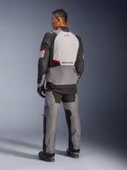 Alpinestars Andes V4 Drystar® Jas, donkergrijs en Ice Gray met zwarte en felrode accenten, achteraanzicht met lichtgrijs paneel en rood sterlogo, gecombineerd met bijpassende adventure broek en zwarte handschoenen, technische motoruitrusting voor alle weersomstandigheden.