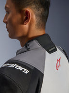 Alpinestars Andes V4 Drystar® Jas, close-up van de kraag en de bovenrug, donkergrijs en ijsgrijs met zwarte accenten, rood sterlogo, voorzien van een trekkoordversteller bij de kraag en Alpinestars-branding, duurzame textielconstructie