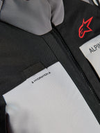 Alpinestars Andes V4 Drystar® jas, close-up detail van de borst, donkergrijze en Ice Gray panelen met zwarte textielversterkingen, voorzien van een rood Alpinestars-logo en een lus voor de hydratatieslang met 'HYDRATION'-label