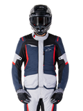 Alpinestars ST-1 Waterproof Jacket, adventure touring jas, donkerblauw, zwart en felrood, gedragen met een zwarte adventure helm en grijze handschoenen, voorzien van lichtgrijze panelen en rode accenten op de schouders en ritsen, strak ontwerp met Alpinestars-branding op de borst, duurzame waterdichte motorkleding