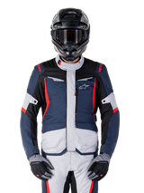 Alpinestars ST-1 Waterproof Jacket, Adventure Touring Jacket, Dark Blue Black and Bright Red, worn with a black adventure helmet and grey gloves, featuring light grey panels and red accents on shoulders and zippers, sleek design with Alpinestars branding on chest, durable waterproof gear for motorcycle riding