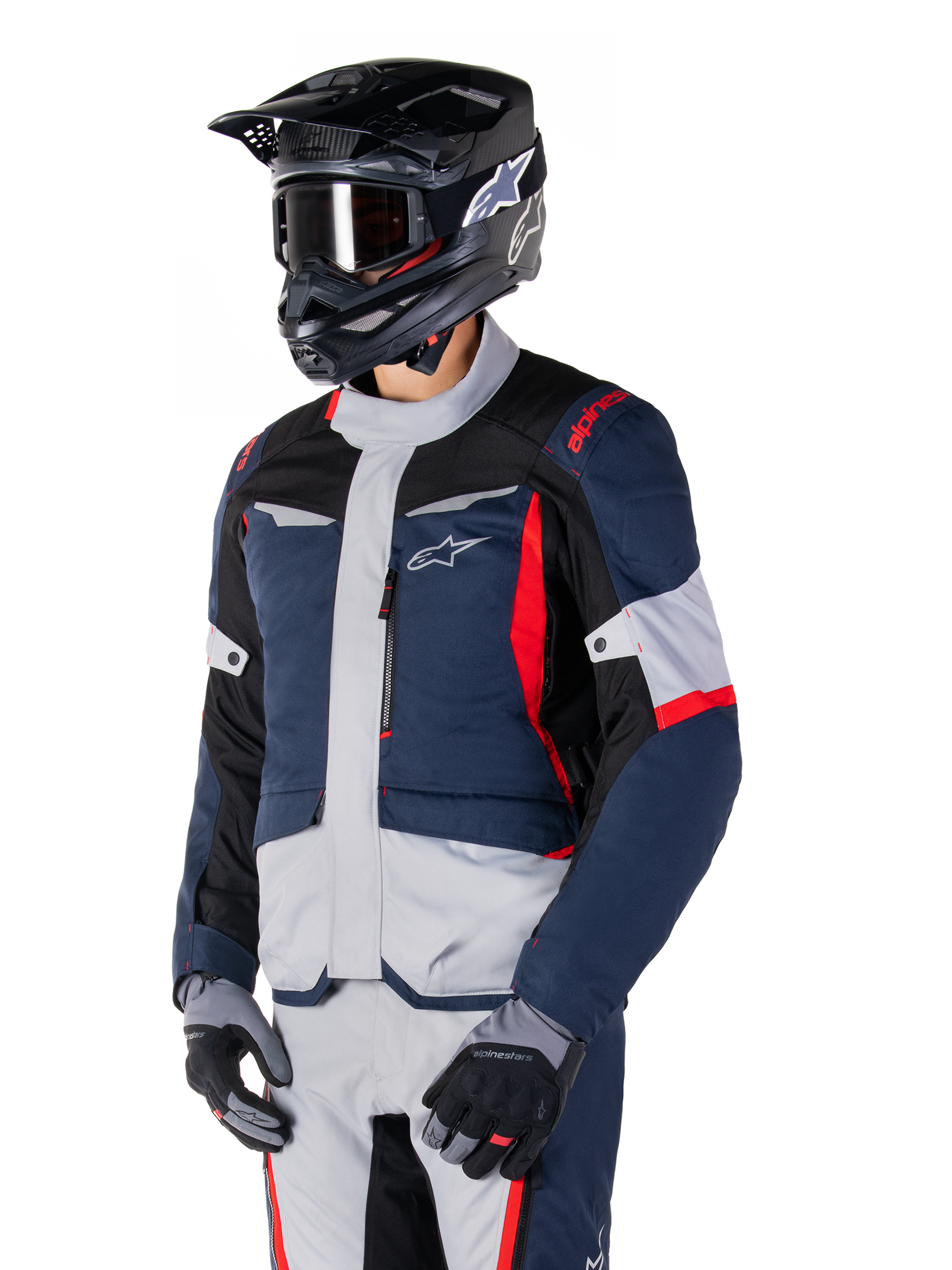 Alpinestars ST-1 Waterproof Jacket, adventure touring motorjas in donkerblauw, zwart en felrood, gedragen met een zwarte helm en grijze handschoenen, voorzien van een modern design met functionele zakken en Alpinestars-branding.