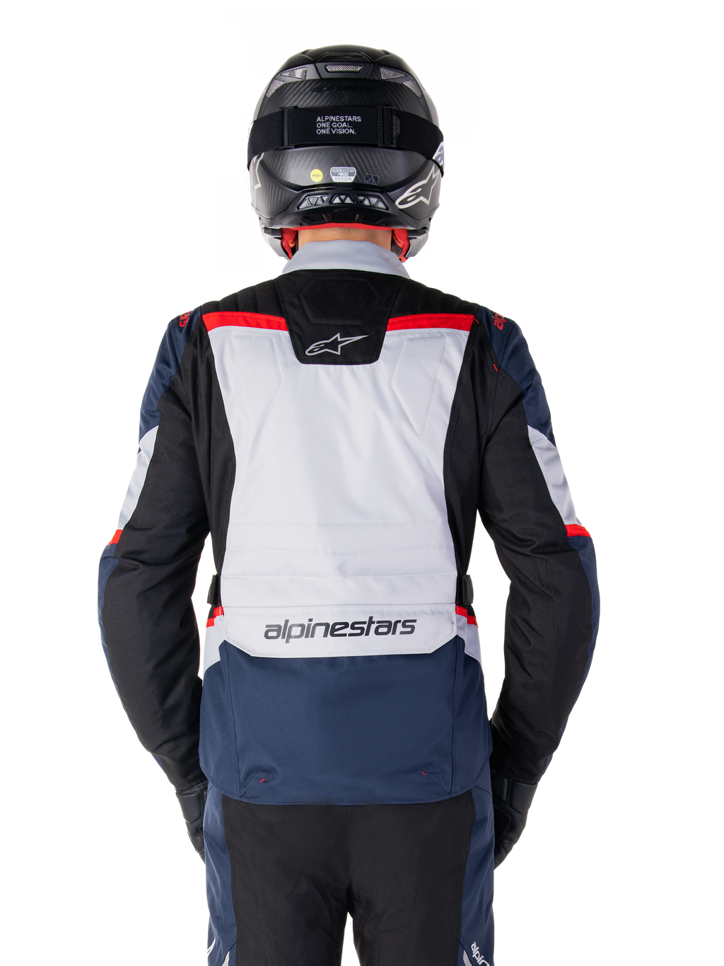 Alpinestars ST-1 Waterproof Jacket, donkerblauw, zwart en helderrood, achteraanzicht met lichtgrijs rugpaneel en merknaam, adventure touring motorjas gedragen met zwarte helm en handschoenen, gestroomlijnd ontwerp voor alle weersomstandigheden