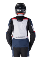Alpinestars ST-1 Waterproof Jacket, donkerblauw, zwart en helderrood, achteraanzicht met lichtgrijs rugpaneel en merknaam, adventure touring motorjas gedragen met zwarte helm en handschoenen, gestroomlijnd ontwerp voor alle weersomstandigheden