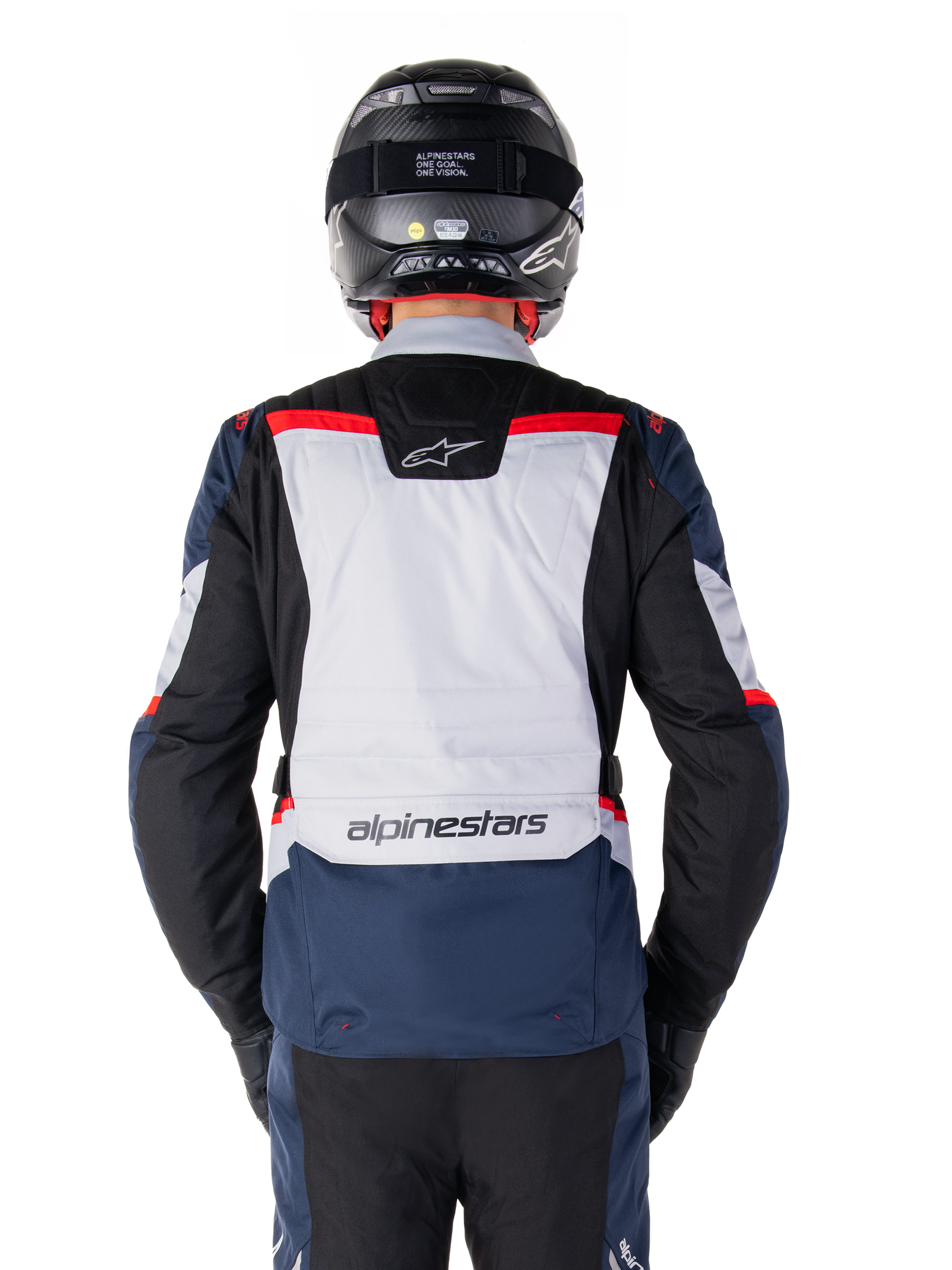 Alpinestars ST-1 Waterproof Jacket, donkerblauw, zwart en helderrood, achteraanzicht met lichtgrijs rugpaneel en merknaam, adventure touring motorjas gedragen met zwarte helm en handschoenen, gestroomlijnd ontwerp voor alle weersomstandigheden