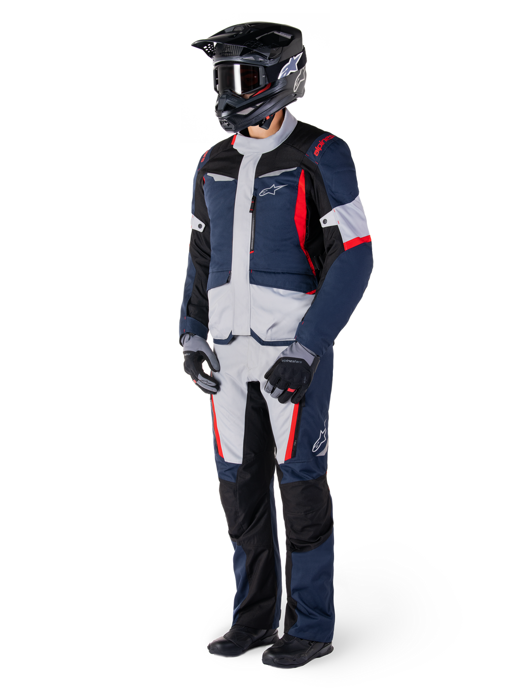 Alpinestars ST-1 Waterproof Jacket, adventure touring jas, donkerblauw, zwart en felrood, gedragen door een rijder met bijpassende broek, zwarte adventure helm, handschoenen en laarzen, voorzien van grijze panelen en rode accenten, gestroomlijnd adventure-geïnspireerd ontwerp met Alpinestars-logo's