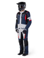 Alpinestars ST-1 Waterproof Jacket, adventure touring jas, donkerblauw, zwart en felrood, gedragen door een rijder met bijpassende broek, zwarte adventure helm, handschoenen en laarzen, voorzien van grijze panelen en rode accenten, gestroomlijnd adventure-geïnspireerd ontwerp met Alpinestars-logo's