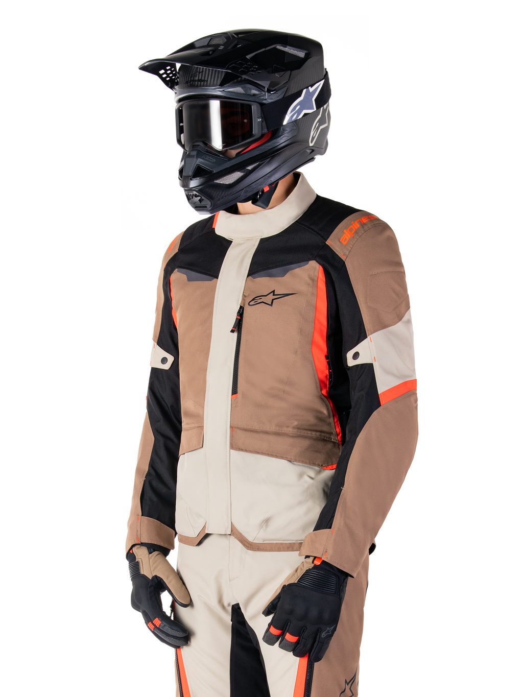Alpinestars ST-1 Waterproof jas, adventure touring-jas, Dark Khaki Sand Black en Red Fluo, gedragen door een rijder met een zwarte motorcrosshelm en bril, voorzien van een multi-panel ontwerp met cargozakken en Alpinestars-branding op de borst
