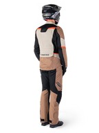 Alpinestars ST-1 Waterproof Jas, adventure touring jas, Dark Khaki Sand Black Red Fluo, achteraanzicht gedragen met bijpassende broek en zwarte helm, voorzien van kleurvlakken en fluorescerende rode accenten.